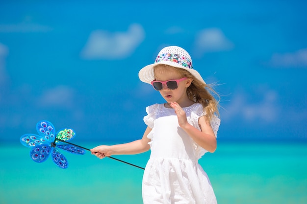 Adorable happy smiling little girl in hat on beach vacation