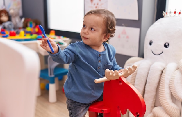 Adorable hispanic boy playing with reindeer rocking at kindergarten