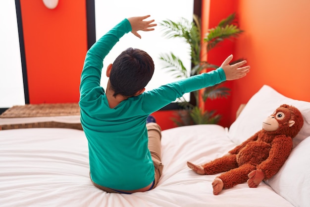 Adorable hispanic boy waking up stretching arms at bedroom