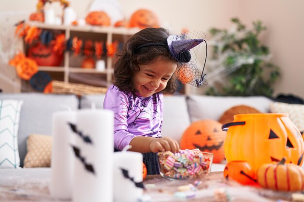 Adorable hispanic toddler having halloween party holding sweets at home