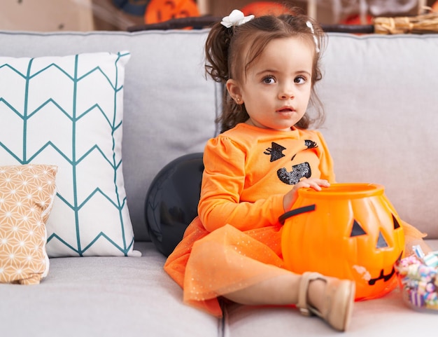 Adorable hispanic toddler having halloween party sitting on sofa at home