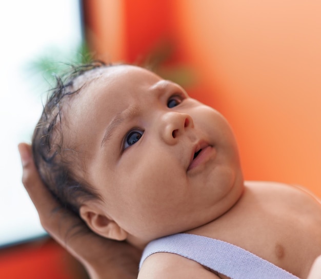 Adorable hispanic toddler on mother arms at home