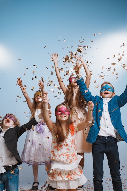 Adorable kids have fun together throw colourful confetti at birthday party. They playing together in different games, spending time in decorated studio. Children and events concept