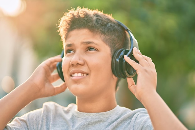 Adorable latin boy smiling happy using headphones at the city