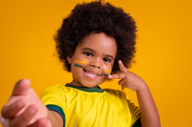 黄色のTシャツで自分撮りをしている愛らしい小さなアフロの女の子ブラジルのファン