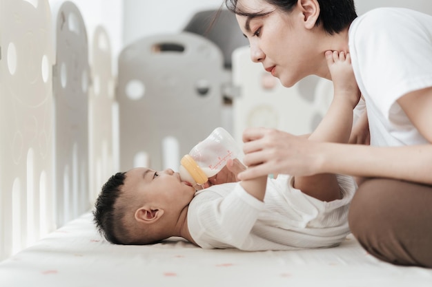 아기 병에서 우유를 마시는 사랑스러운 작은 아시아 아기 아시안 어머니는 아기를 돌보는 사랑스러운 아기 우유 병에서 을 먹이는 개념 아기 건강 관리