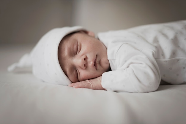 Photo adorable little baby sleeping on white sheets