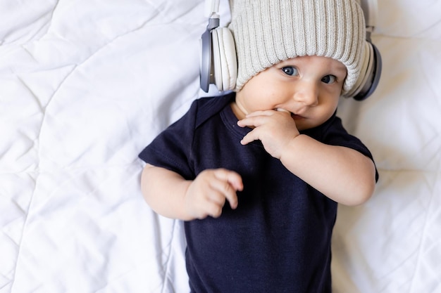 Adorable little boy in hat with headphones laying on blanket, card, space for text, banner