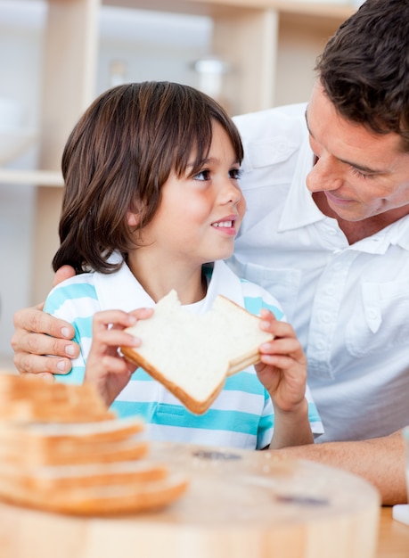 愛らしい小さな男の子と彼の父親はパンを食べる