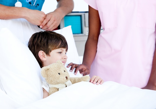 Adorable little boy hugging a teddy bear lying 