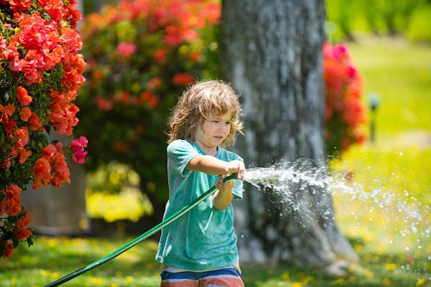 愛らしい男の子は、家の外で植物に水をやっています。自然の中の木のための子供と子供の教育のための植物成長学習活動の概念