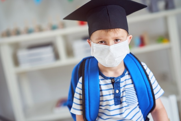 Adorable little boy in kindergarten with mask on due to coronavirus pandemic