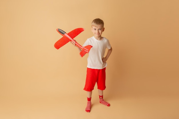 Adorable little boy playing with red airplane on the light background Entertainment concept