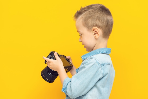 愛らしい小さな男の子がデジタルカメラを研究します。