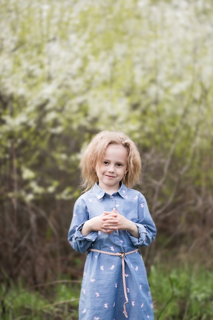 Adorable little caucasian girl of 5 years old in a park standing under blossoming cherry tree