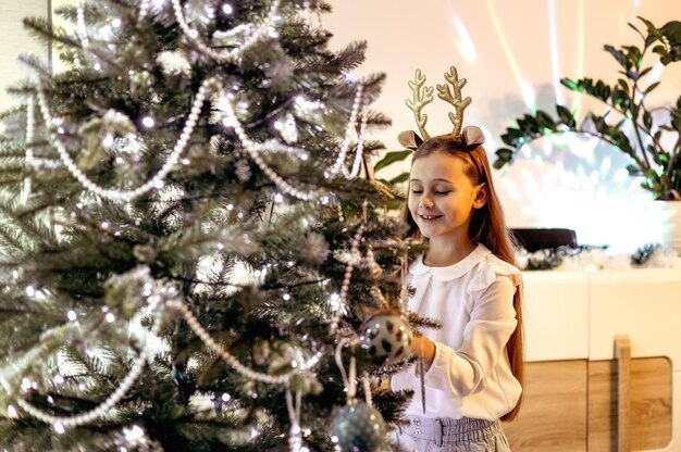 Adorable little child girl decorating Christmas tree at home