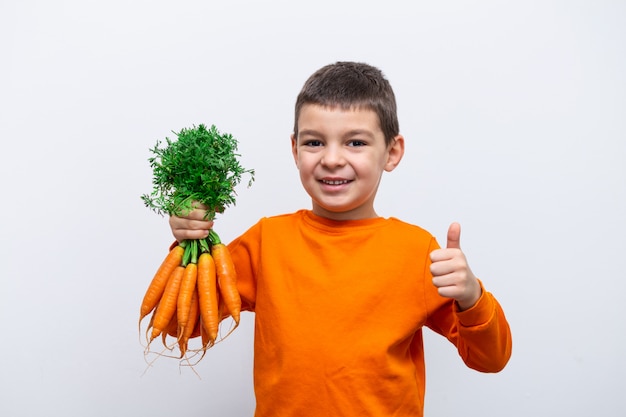 Adorabile bambino con carote. sani ortaggi biologici per bambini. ragazzo del bambino che tiene le carote in sue mani.