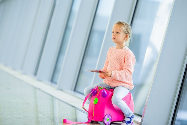 Adorable little girl in airport with her luggage waiting for boarding