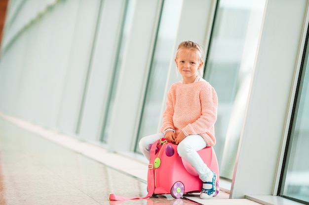 Adorable little girl in airport with her luggage waiting for boarding