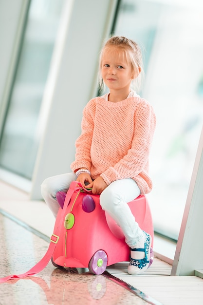 Adorable little girl in airport with her luggage waiting for boarding