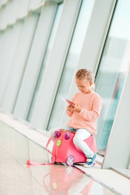 Bambina adorabile in aeroporto con i suoi bagagli che aspettano imbarco