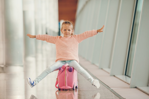 Adorable little girl in airport with her luggage waiting for boarding