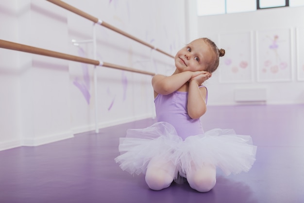 Adorable little girl in ballet outfit practicing at dance class