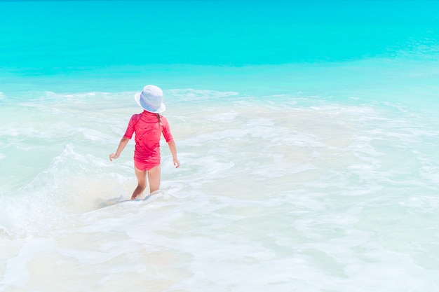 Adorable little girl at beach having a lot of fun in water