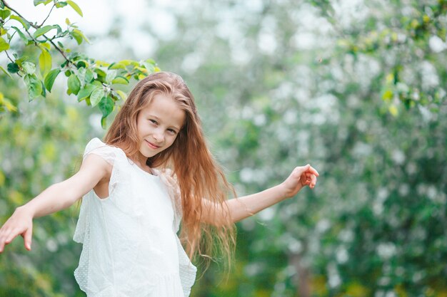 Adorable little girl in blooming apple garden on beautiful spring day