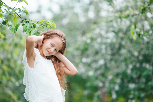 Adorable little girl in blooming apple garden on beautiful spring day