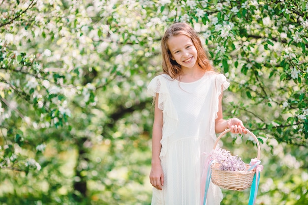 Adorable little girl in blooming apple garden on beautiful spring day