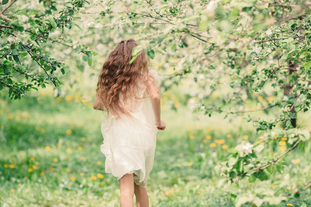 Adorable little girl in blooming apple garden on beautiful spring day