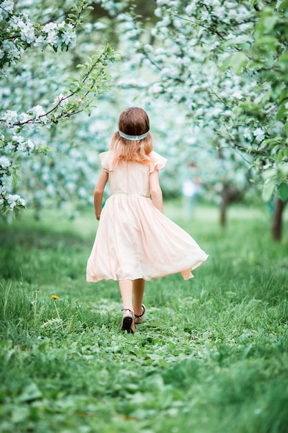 봄 날에 피 사과 나무 정원에서 사랑스러운 어린 소녀