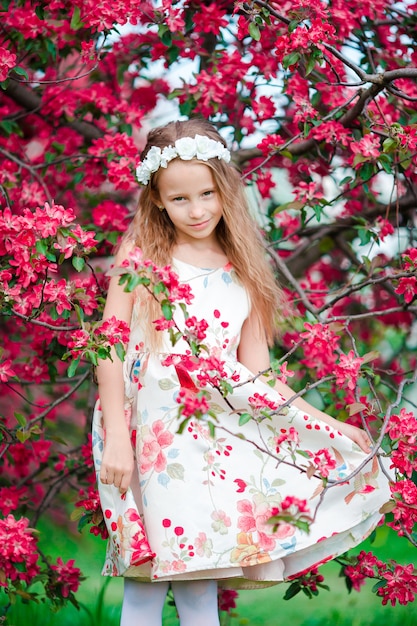 Adorable little girl in blooming apple tree garden on spring day