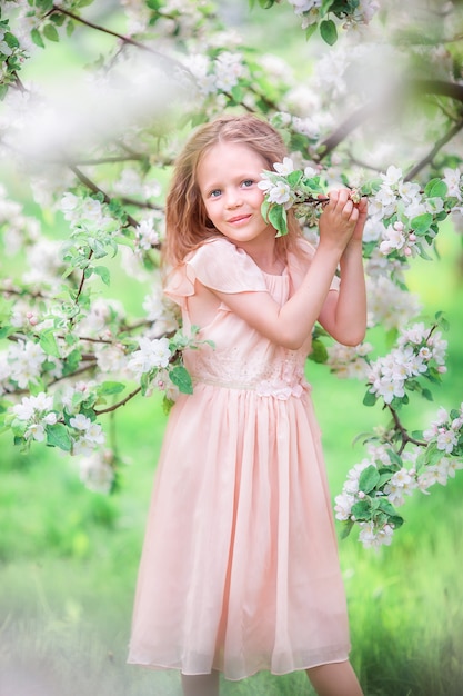 Adorable little girl in blooming cherry tree garden outdoors