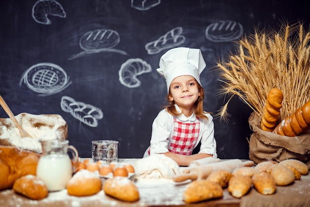 Adorable little girl in chef hat making dough