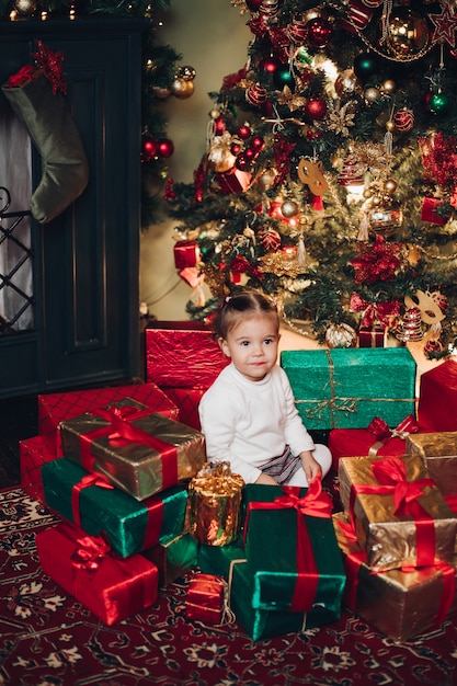 Adorable little girl in Christmas presents. Christmas tree.