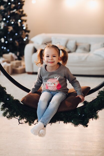 Adorabile bambina sull'altalena di natale.