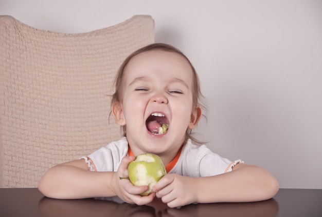 Adorable little girl eating an green apple