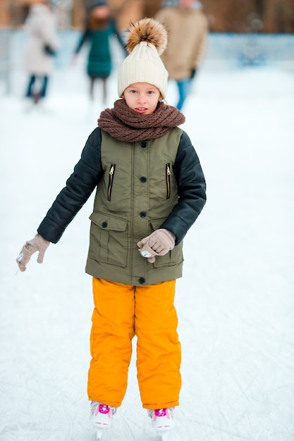 겨울 눈 날 야외에서 스케이트가 사랑스러운 작은 소녀