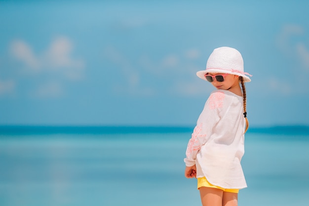 Adorable little girl in hat at beach during summer vacation