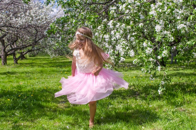 Adorable little girl have fun in blossoming apple orchard