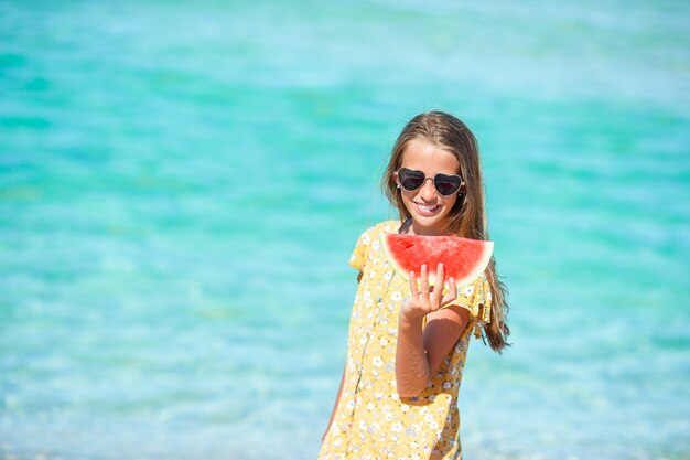 La bambina adorabile si diverte alla spiaggia tropicale durante la vacanza