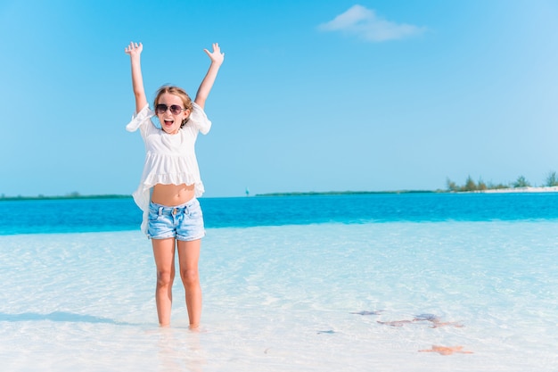 La bambina adorabile si diverte alla spiaggia tropicale durante le vacanze