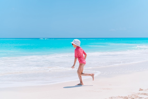 La bambina adorabile si diverte alla spiaggia tropicale durante le vacanze