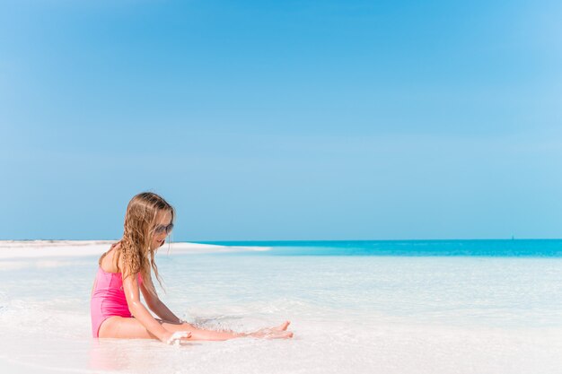 Adorable little girl have fun at tropical beach during vacation