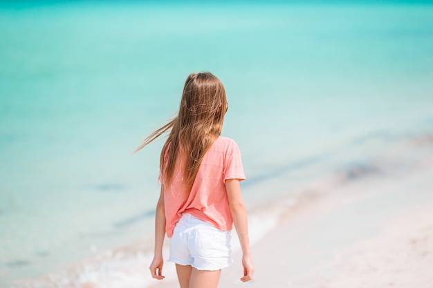 Adorable little girl have fun at tropical beach during vacation