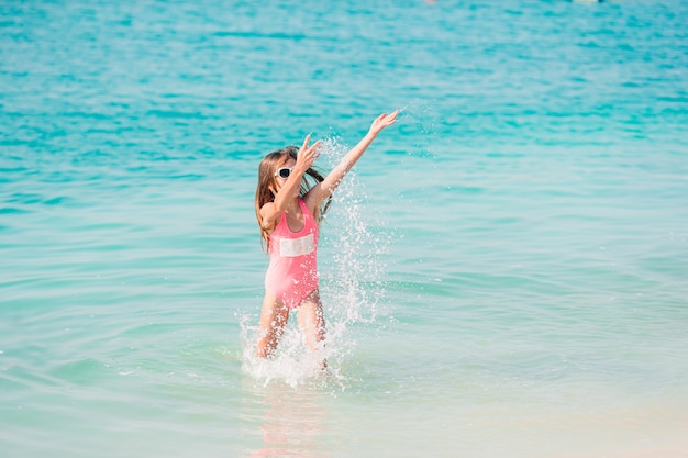 Adorable little girl have fun at tropical beach during vacation