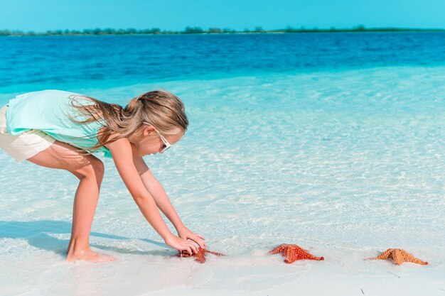 Adorable little girl have fun at tropical beach during vacation