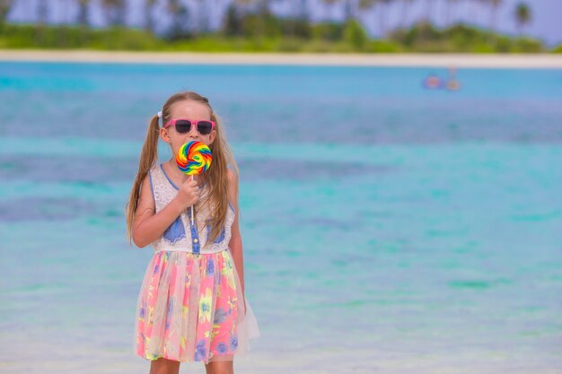 사랑스러운 작은 소녀는 해변에서 롤리팝과 재미가